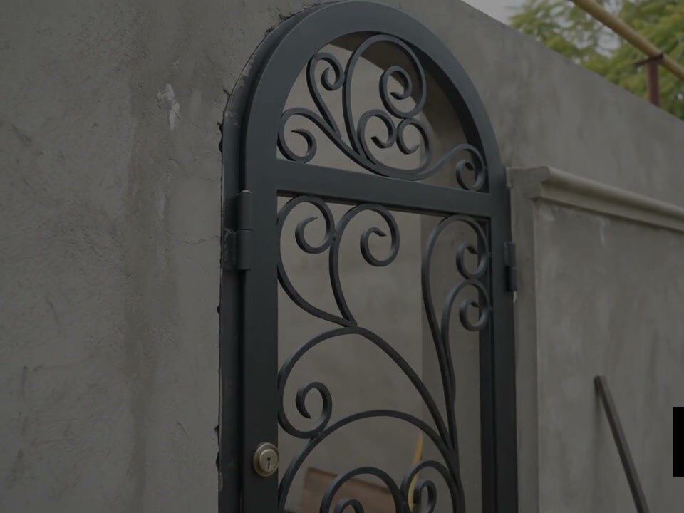 Puerta peatonal de forja artística instalada en el muro de una residencia